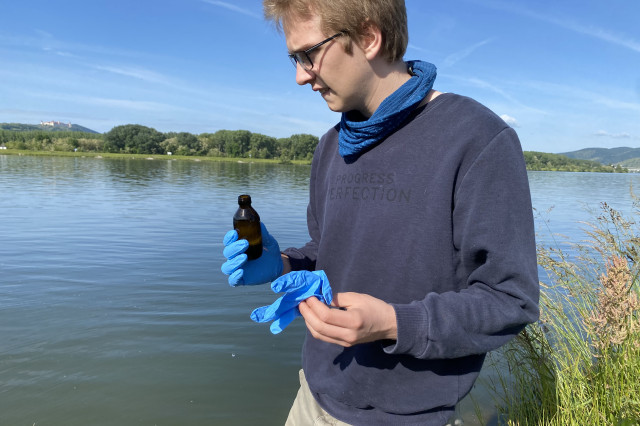 a man stands at the river with a vial in his hand 