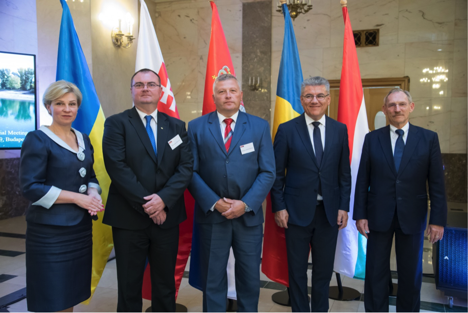 several men and women in business suits standing by flags of different countries in a lobby
