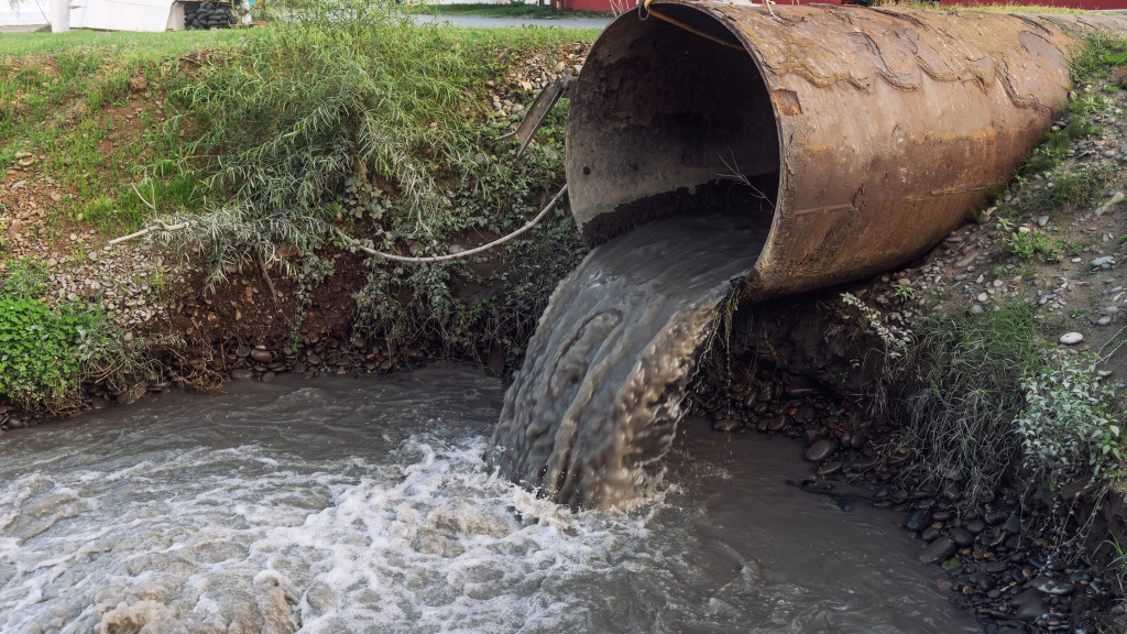 muddy water coming out of a pipe and discharching into a river