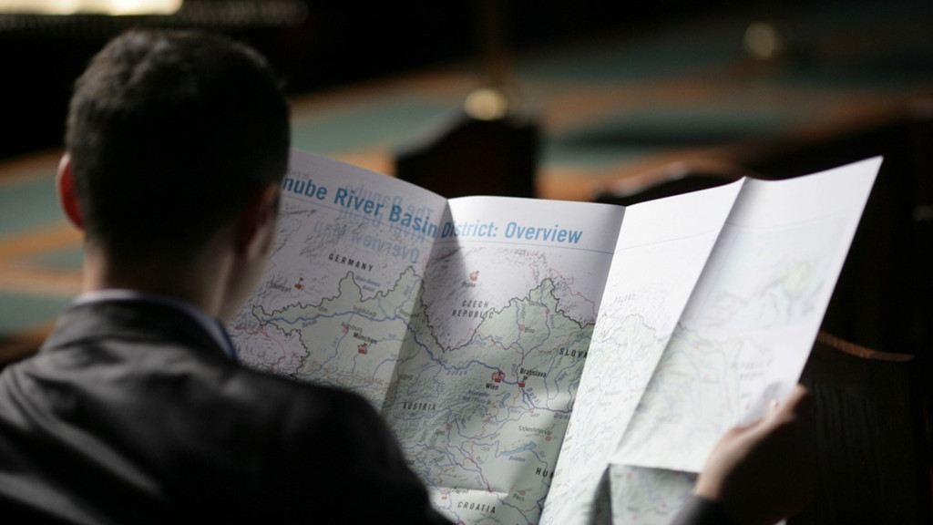 A man from the back reading from a map open in fron of him 