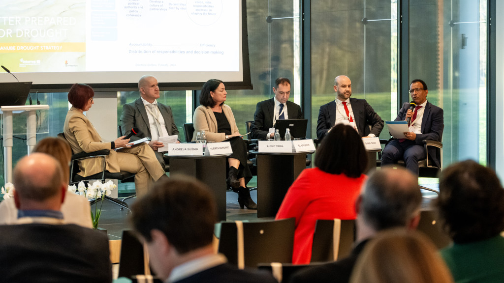 six persons sitting on a panel in front of an audience