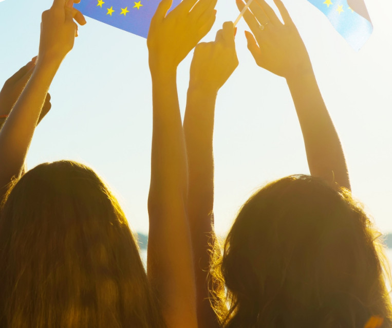 two girls giving their back to the camera, hold an EU flag