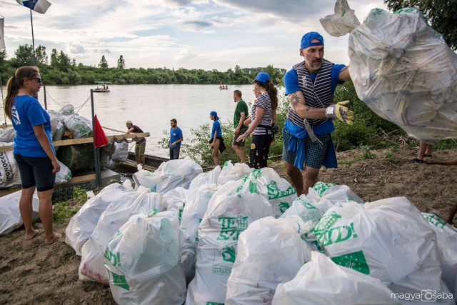 volunteers put collected plastic bottle waste in trash bags