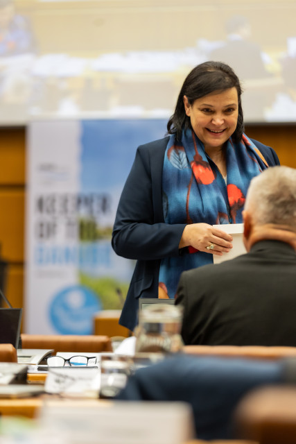 Woman stands and smiles while talking to a man